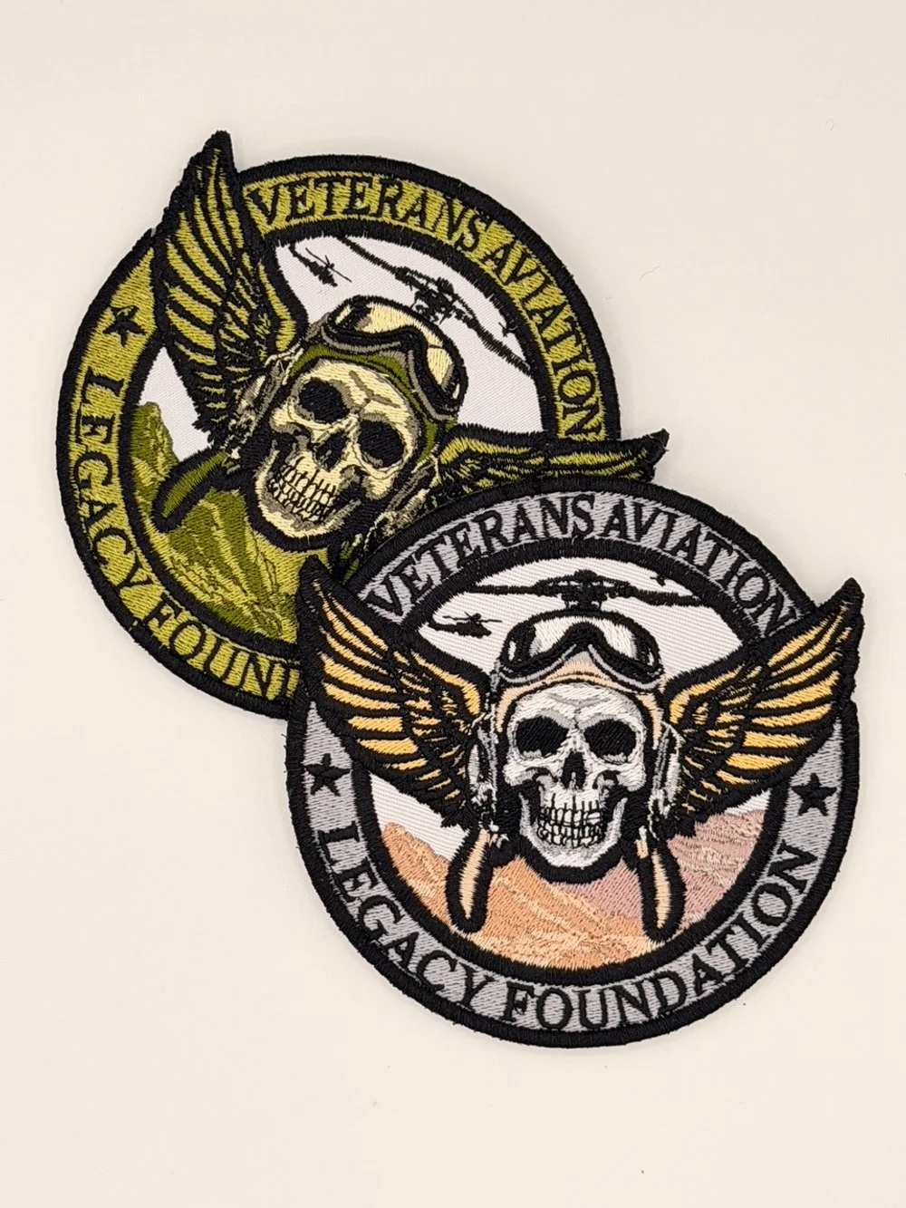 Two embroidered Veterans Aviation Legacy Foundation patches in tan and olive green, featuring pilot skull and wings design symbolizing honor and service.