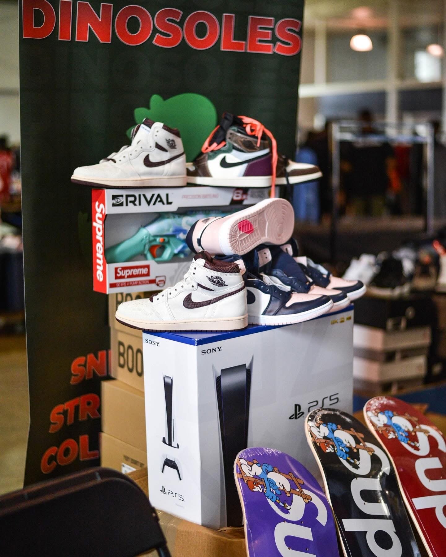 Display of sneakers, skateboard decks, and boxed gaming console at a store, with a sign that says 'Dinoseconds'.