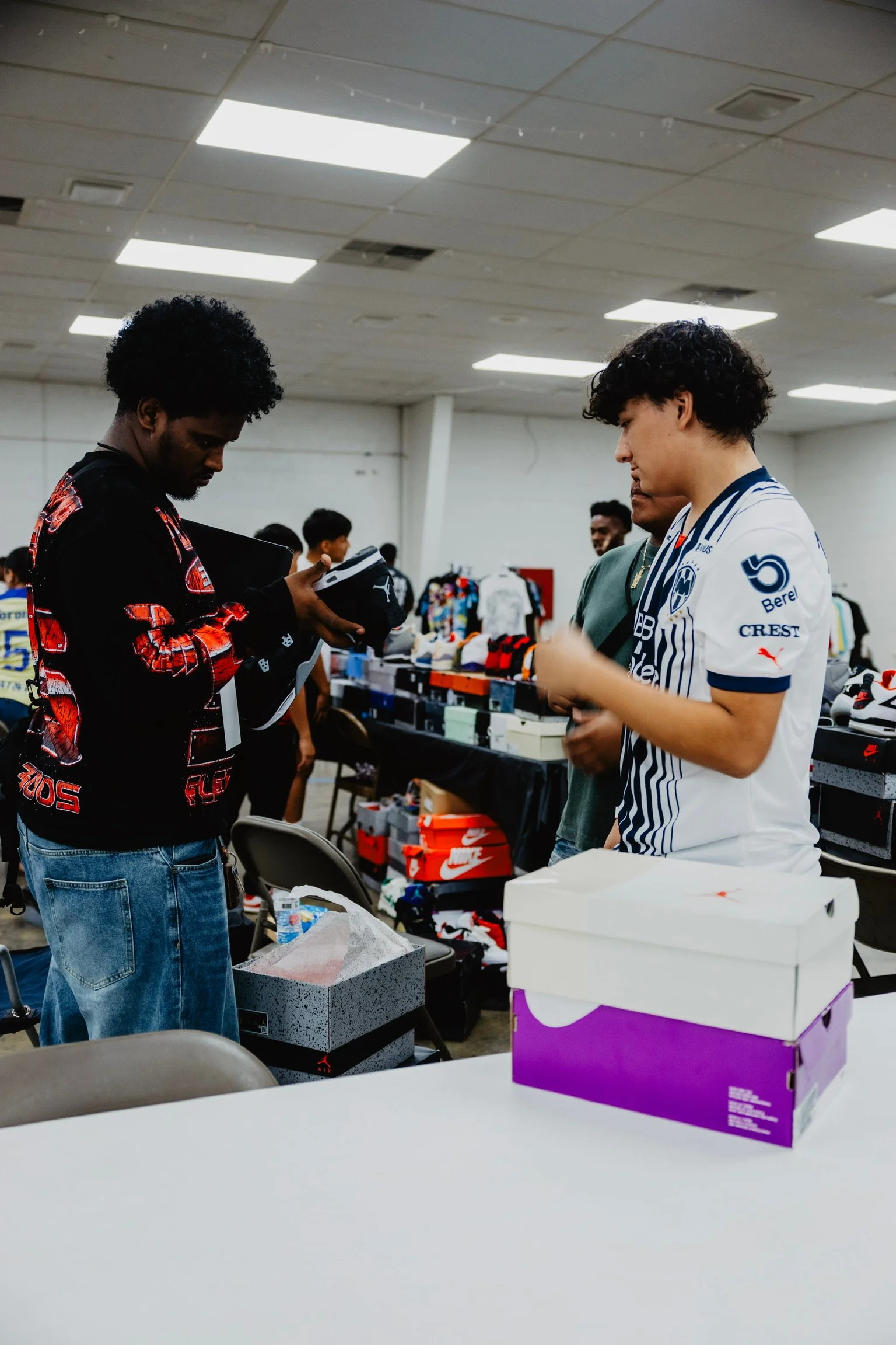 People browsing through sneakers and footwear at an indoor sneaker sale event.