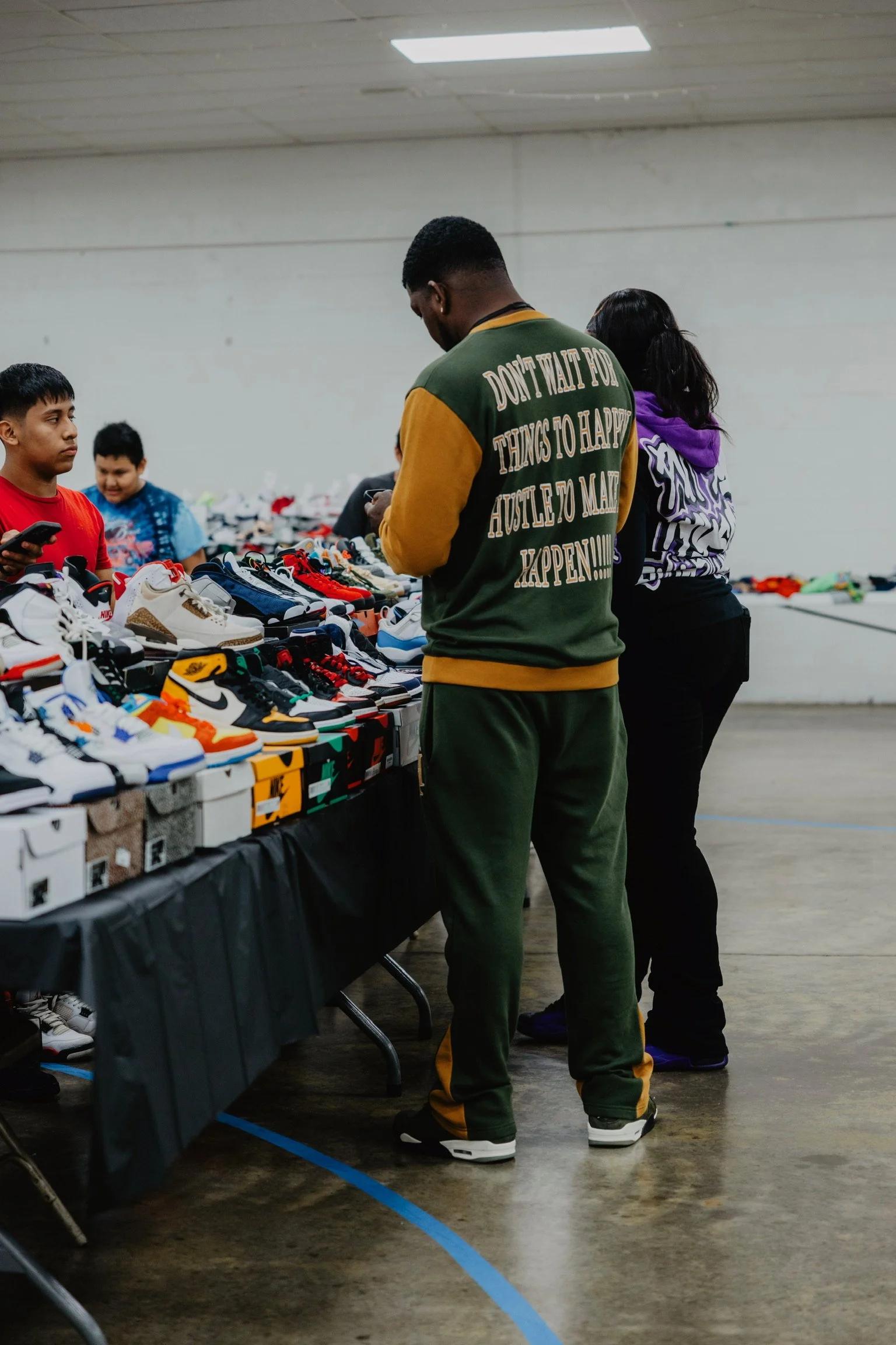 People shopping at a sneaker sale table in an indoor space.