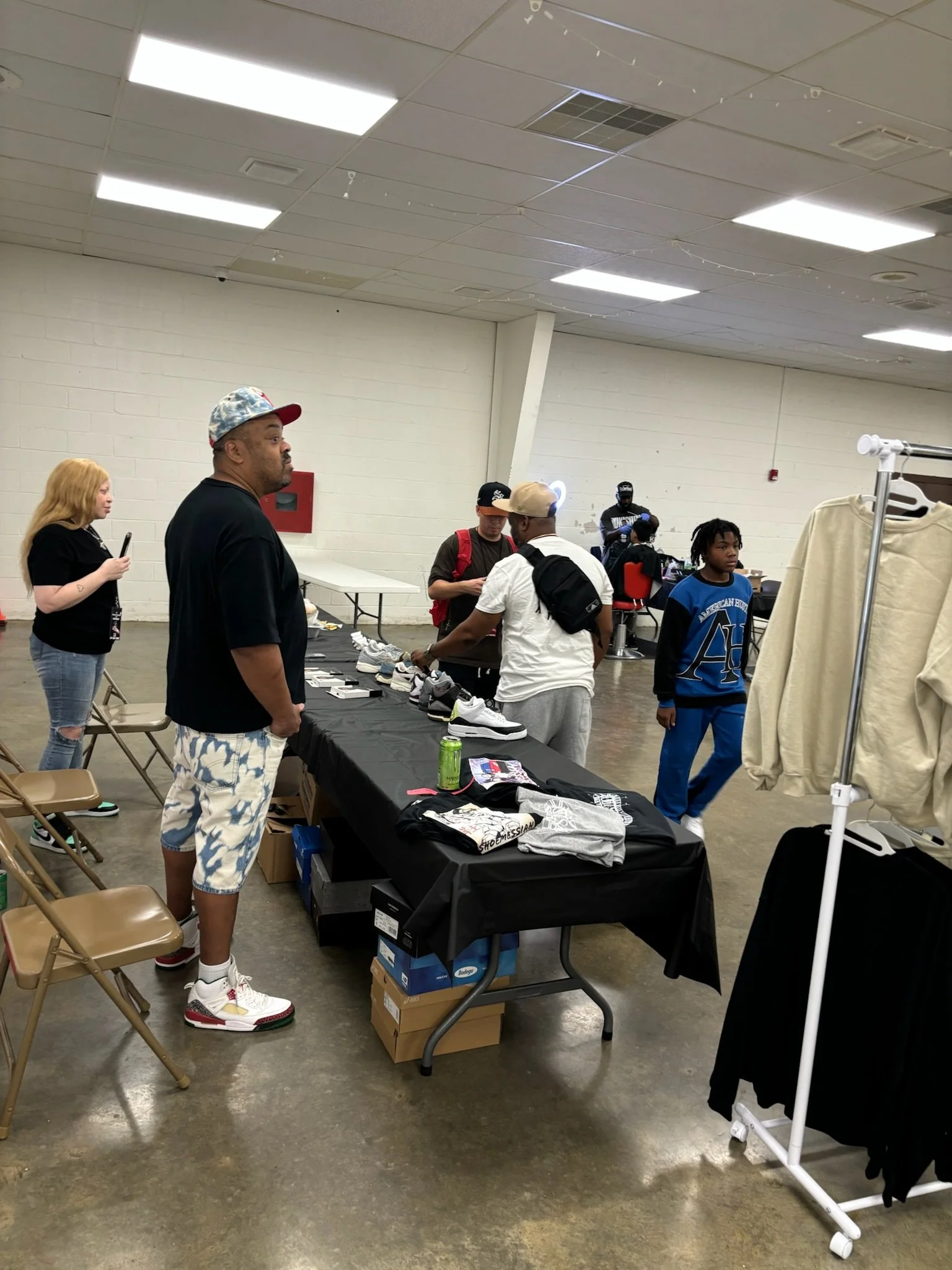 People browsing a table with shoes at an indoor event.