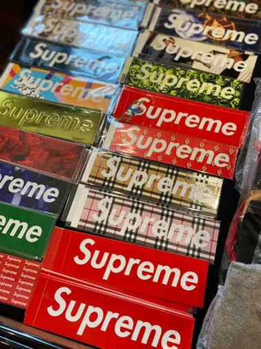 Multiple packs of Supreme-branded lip balms in various colors and designs arranged on a display table.