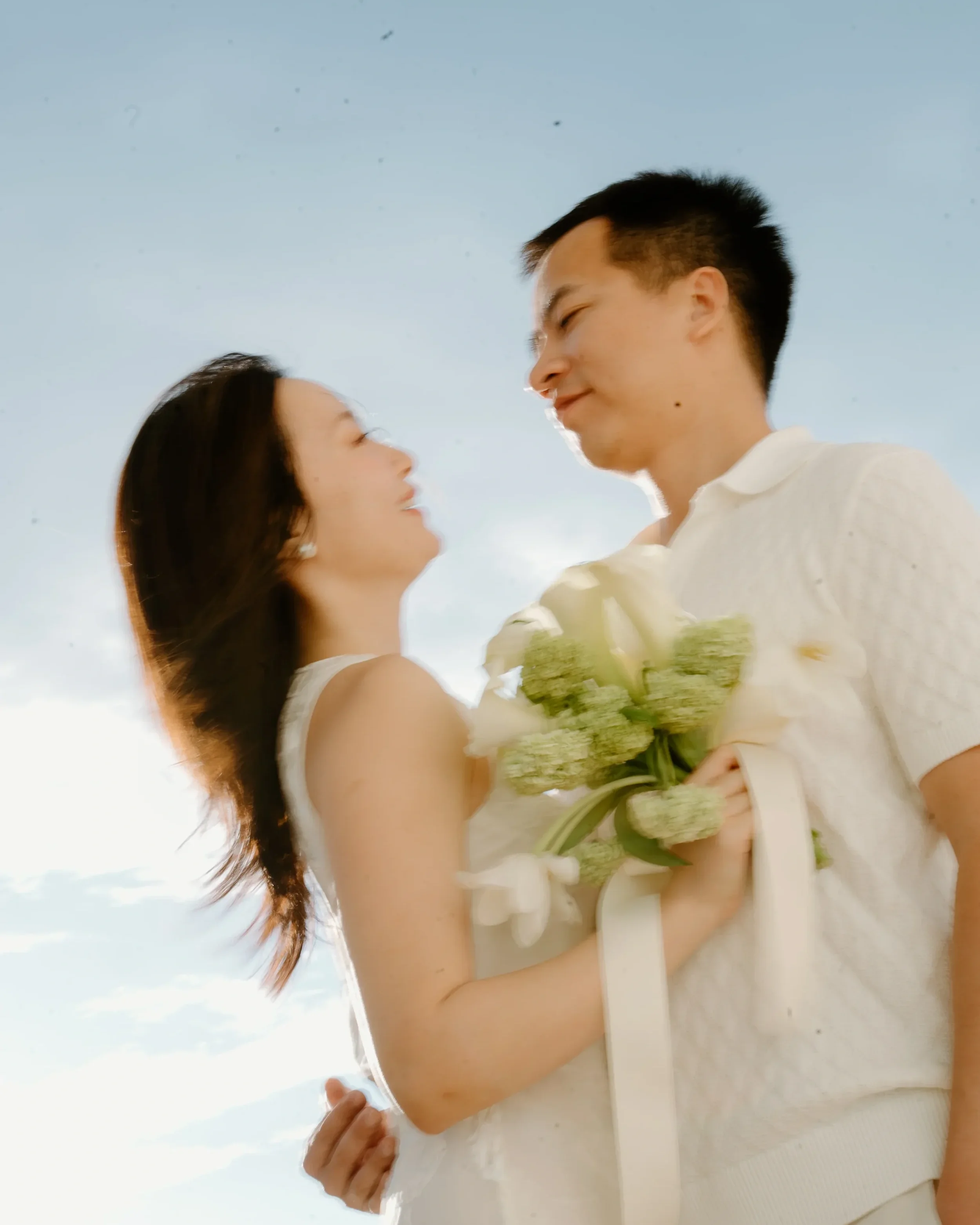 A couple enjoying a romantic moment outdoors, with the woman holding a bouquet of flowers.