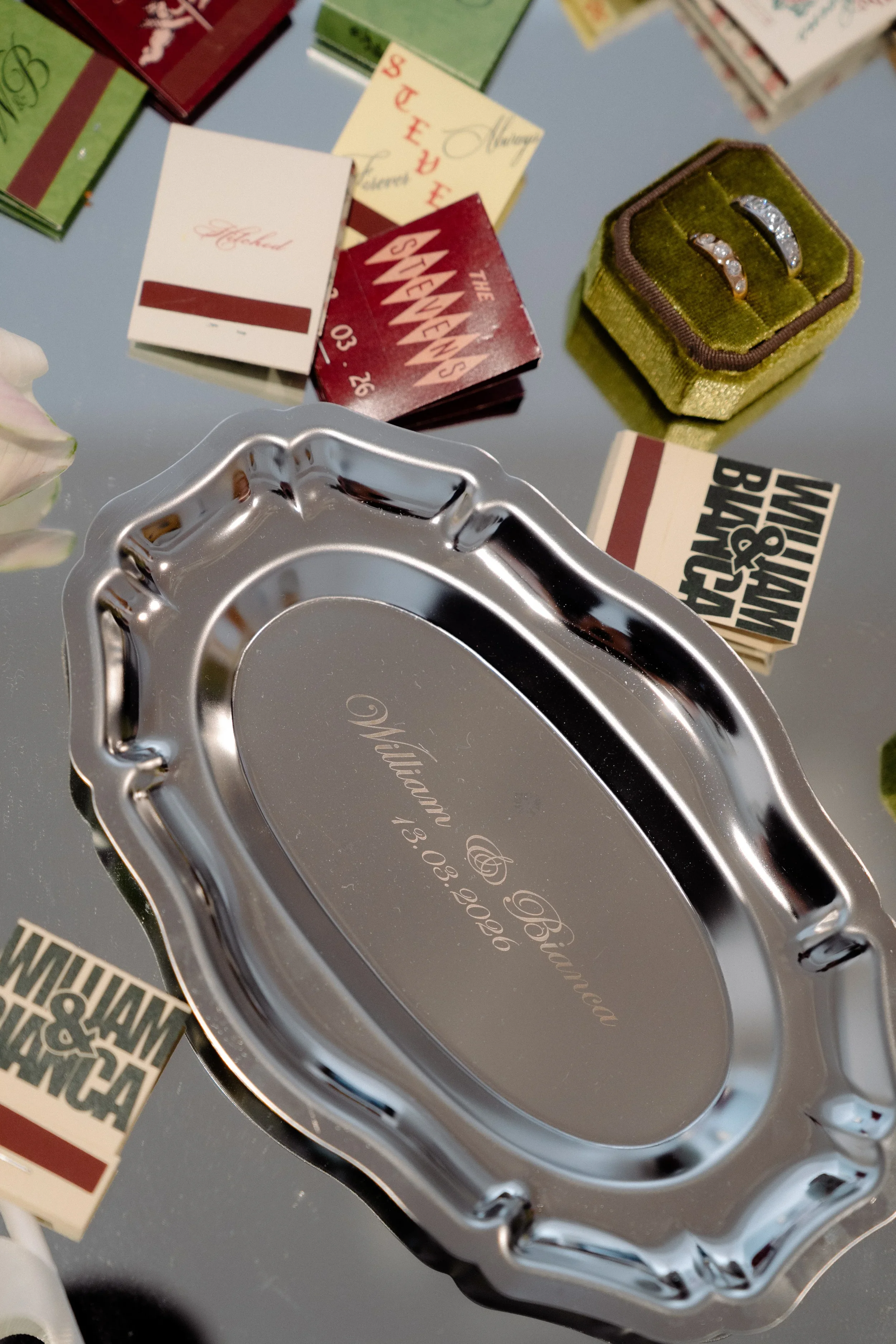 Wedding details including rings, invitation cards, and keepsakes arranged on a tray