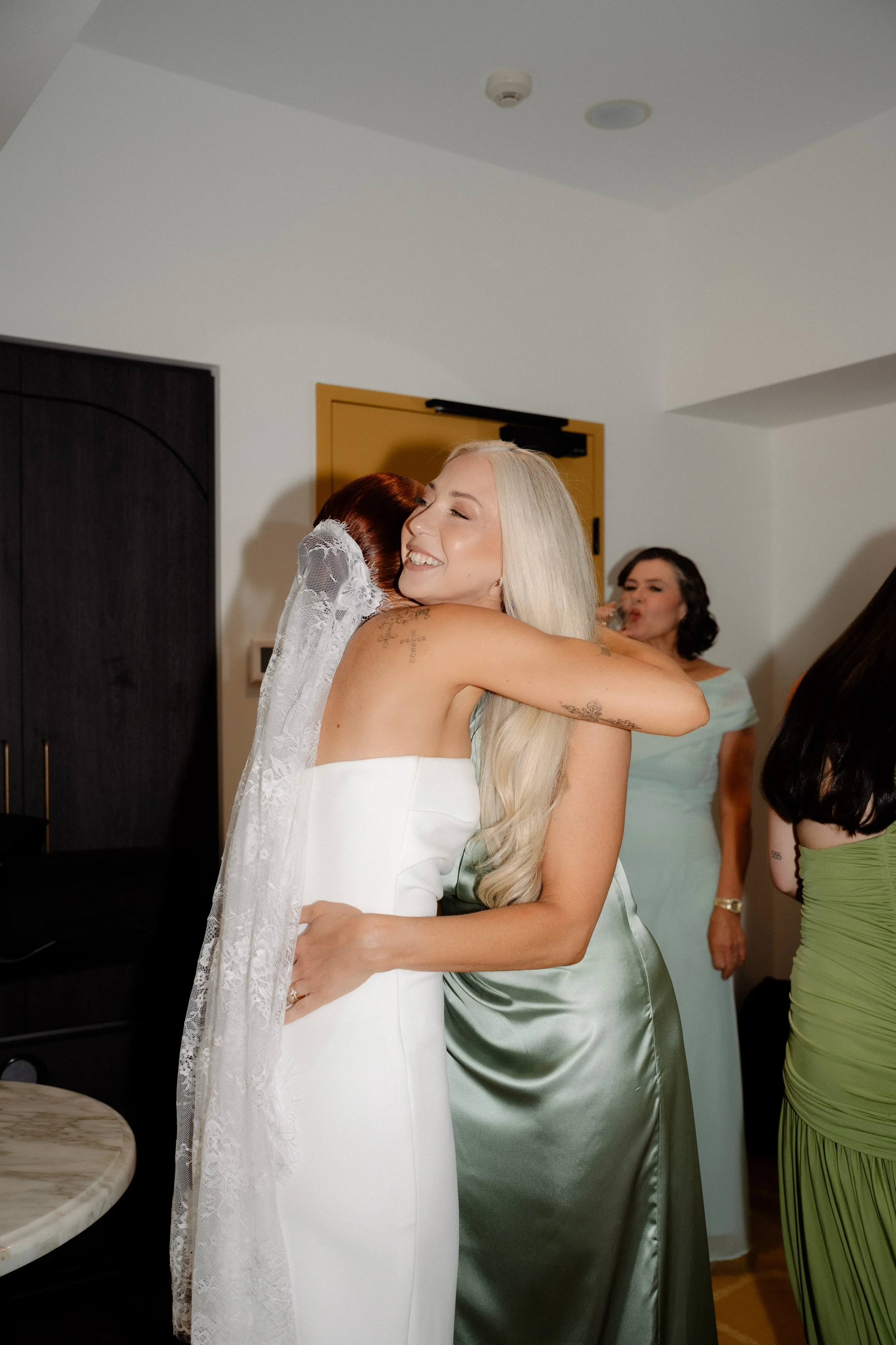 Bride hugging a friend during wedding preparations indoors
