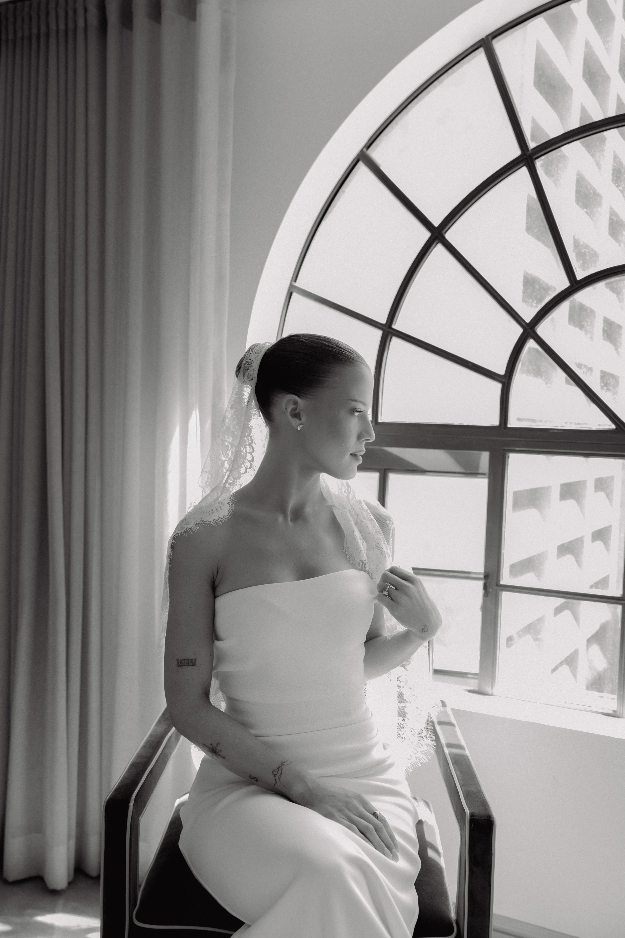 Bride adjusting her veil by the window in a quiet preparation moment