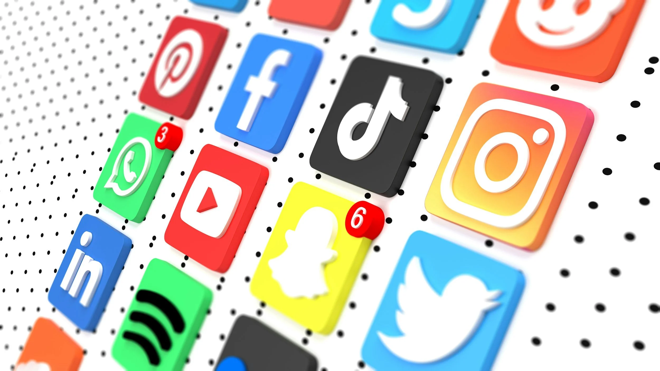 Close-up of various colorful social media icons, including Facebook, Instagram, Twitter, WhatsApp, Pinterest, and TikTok, on a dotted background.