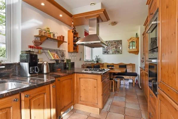 Modern white house with large glass sliding doors, a swimming pool, and a balcony with glass railings under a clear blue sky.