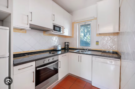Modern white house with large glass sliding doors, a swimming pool, and a balcony with glass railings under a clear blue sky.