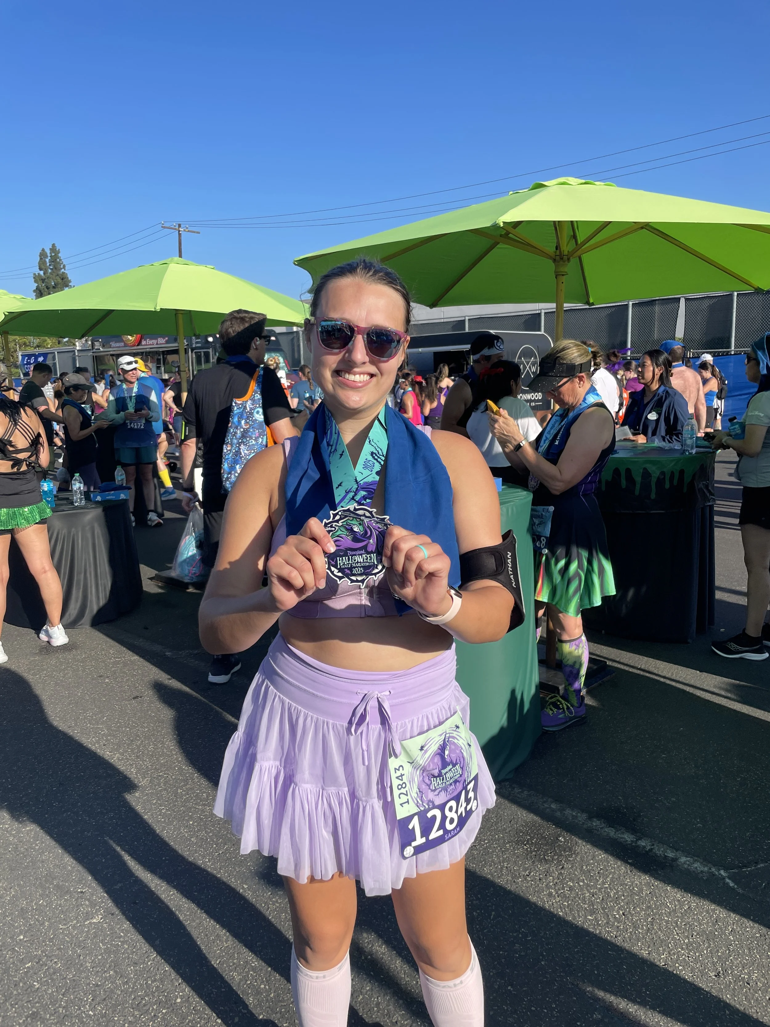 Sarah Hawkins smiling after a race wearing a half-marathon medal