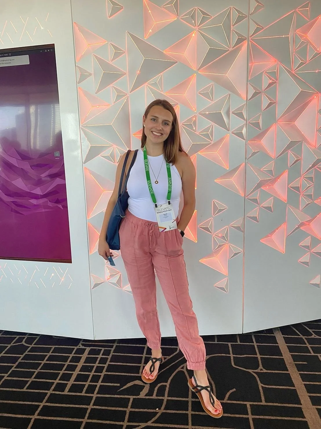 Sarah Hawkins wearing a conference badge and smiling at the camera