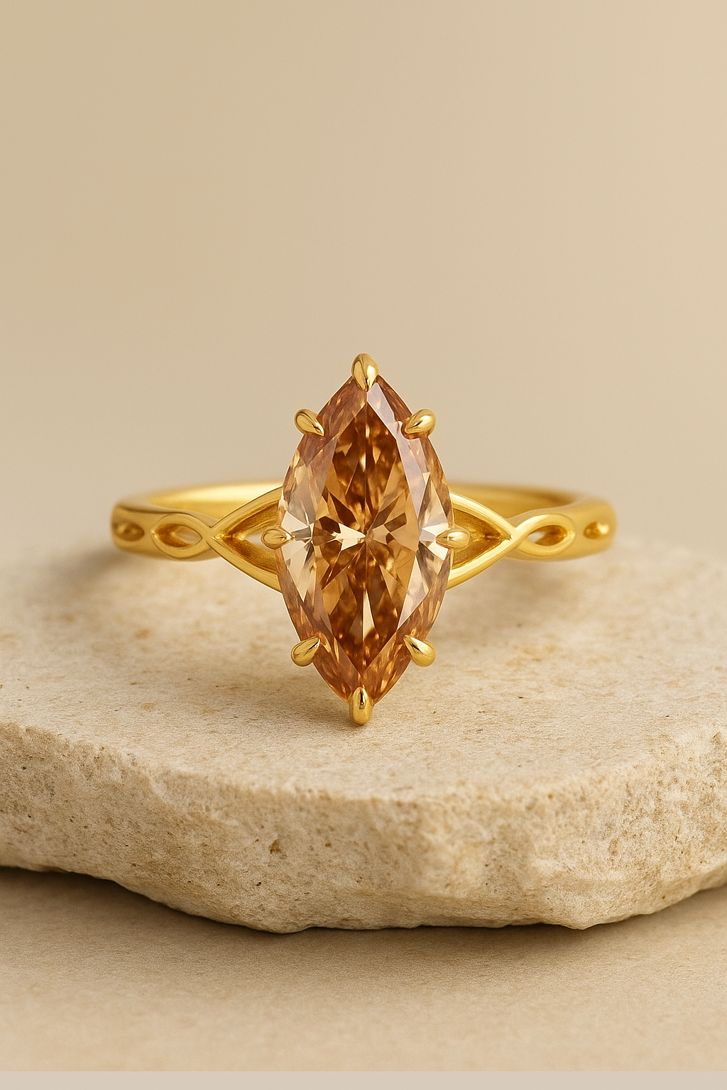 Gold ring with a marquise-cut amber diamond set on a textured beige surface.