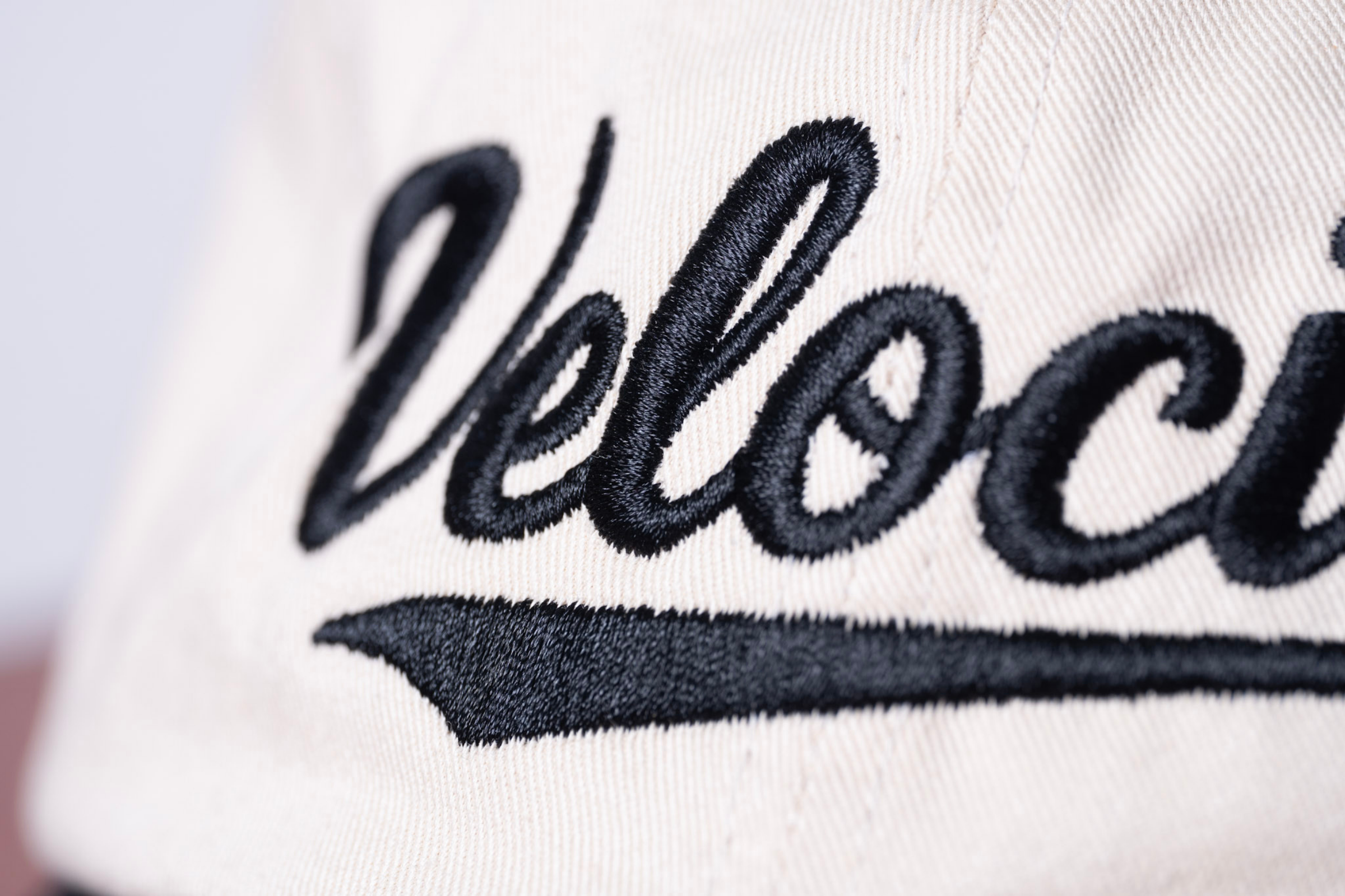 Close-up of beige fabric with black embroidered text and underline.