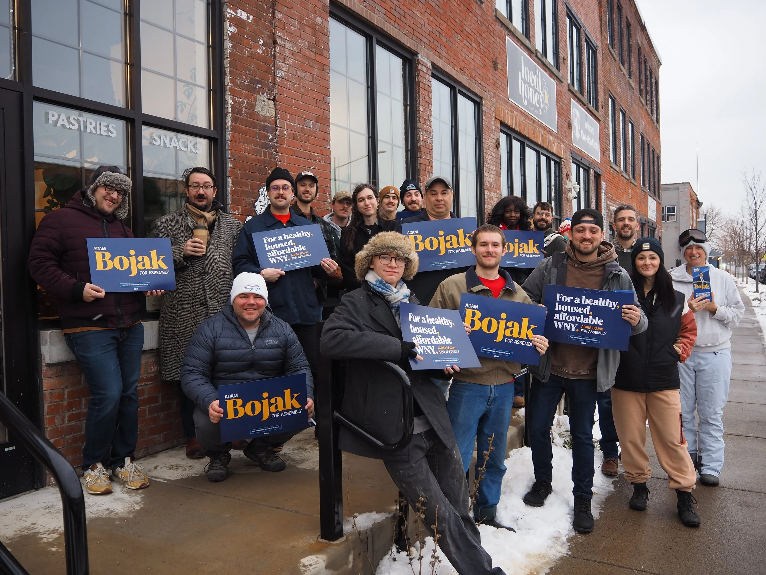 A group of canvassers standing outside, holding Adam Bojak for Assembly Signs