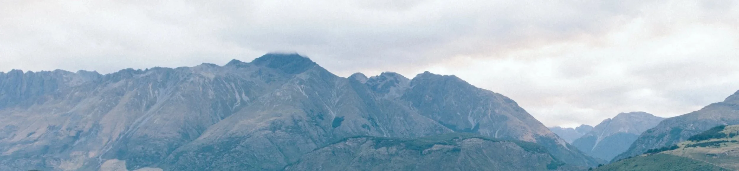 A mountain range with rugged peaks under a cloudy sky.