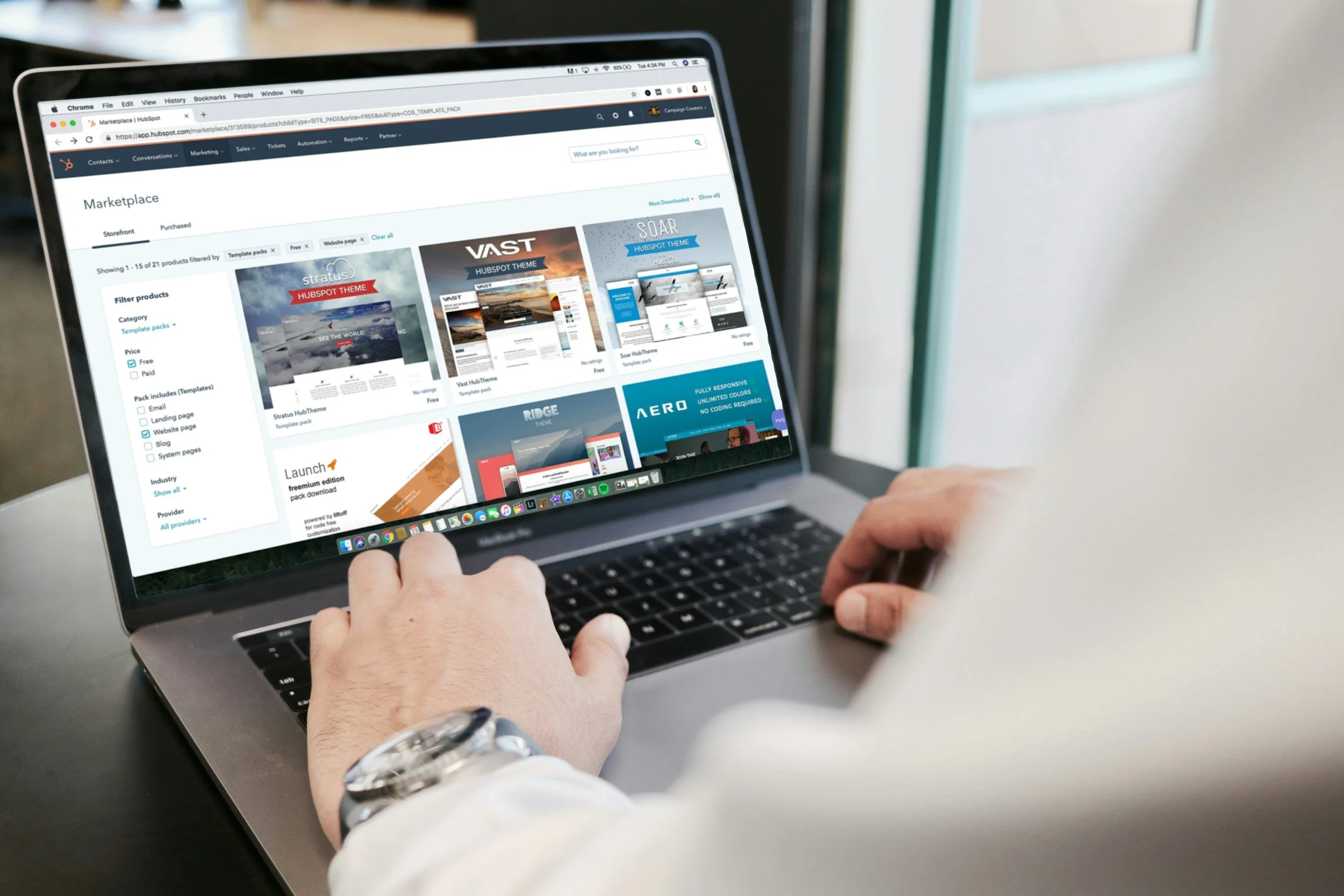 Person browsing the HubSpot marketplace on a MacBook, showing website templates