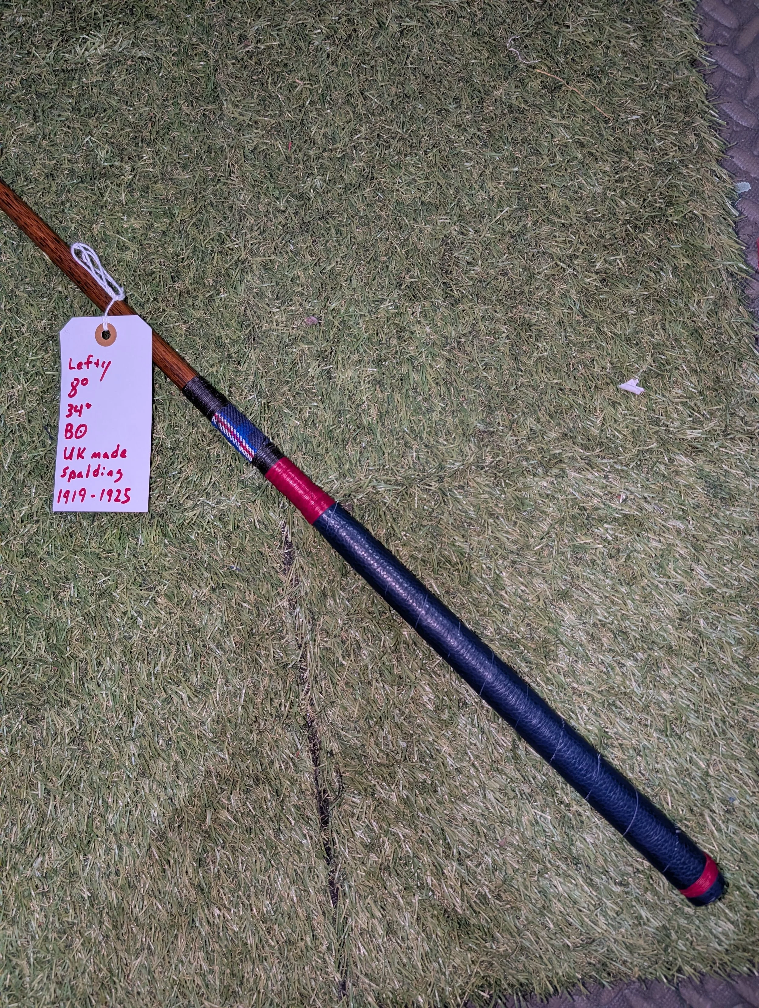 A Spalding hickory golf club putter with tartan fabric and red, black, and blue colors.