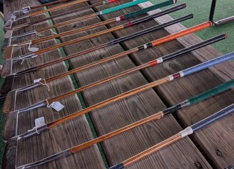 A collection of golf clubs arranged in a row on a wooden surface.