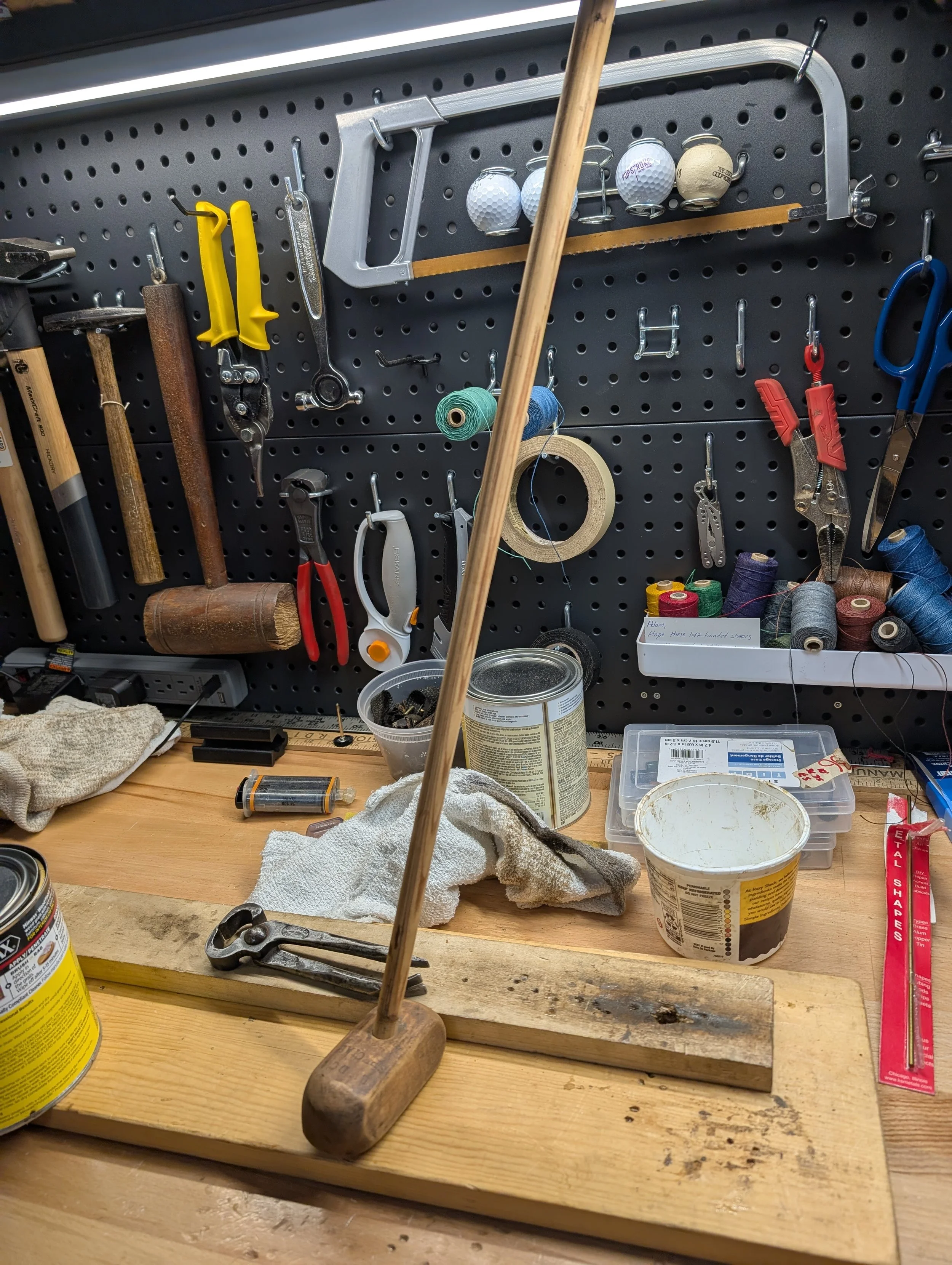 Handmade hickory golf club undergoing restoration on a workbench.