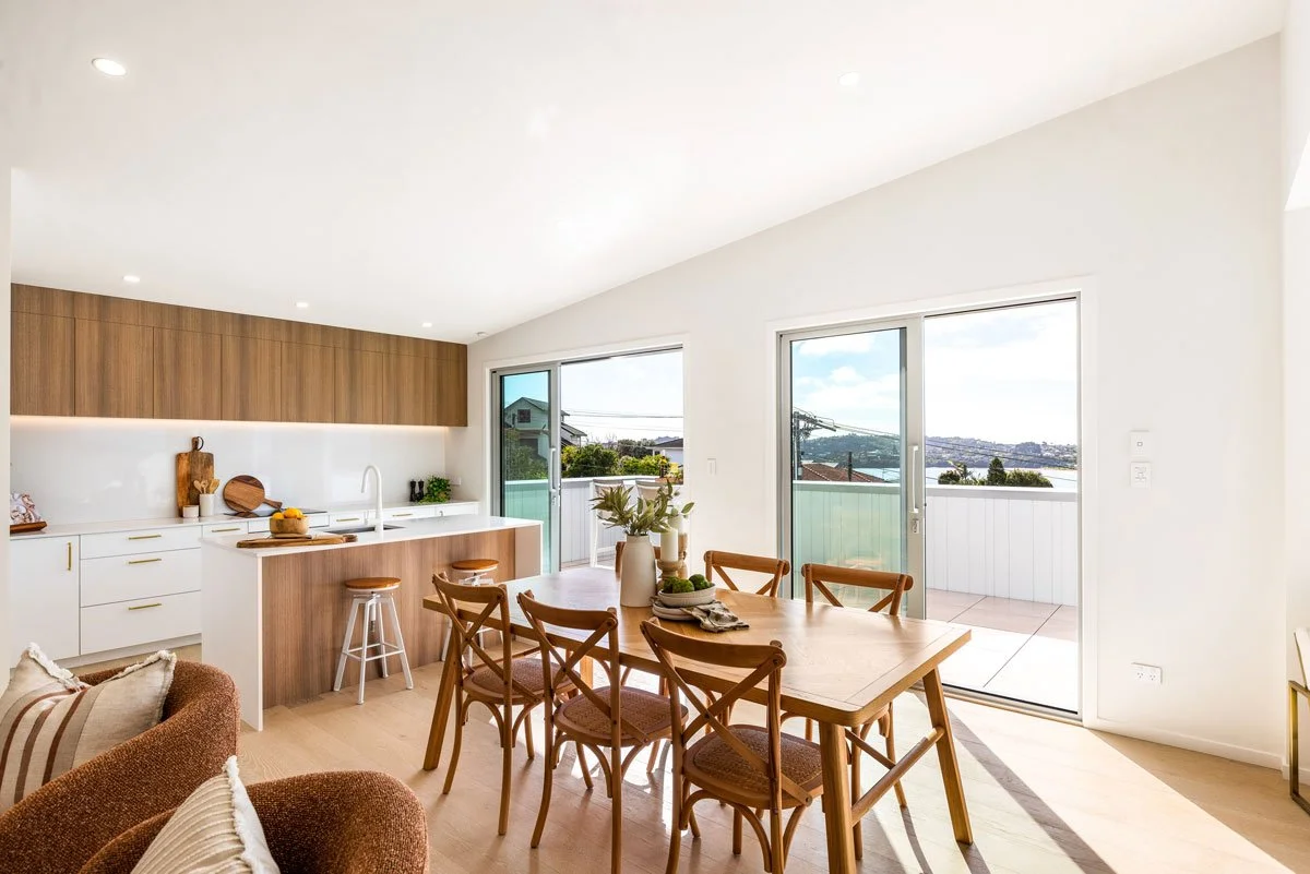 Kitchen island with bar stools and sliding doors opening to deck with water views