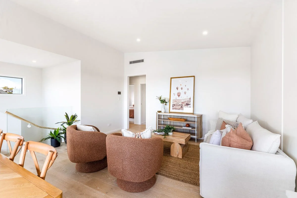 Dining area with timber table, modern chairs, and stairwell access with glass balustrade