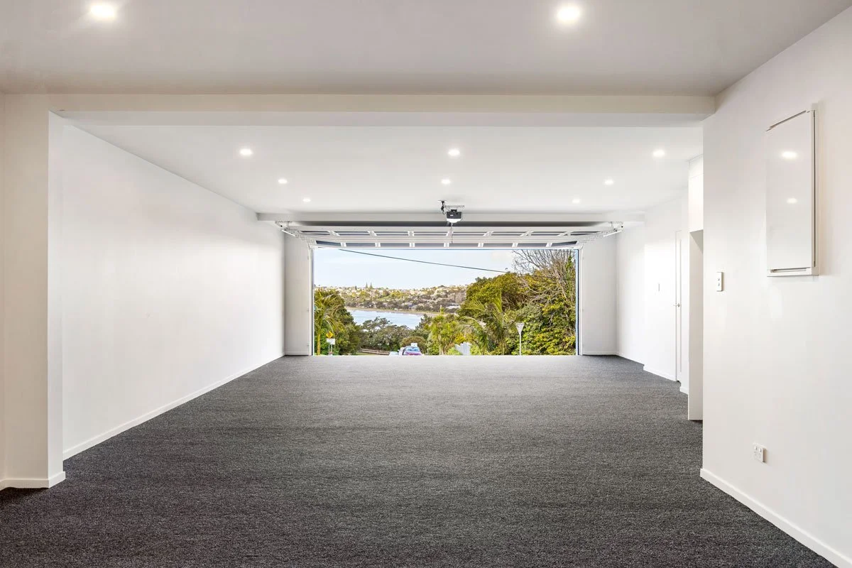 Garage with open door showcasing coastal water views at Bay View home by Ze Build
