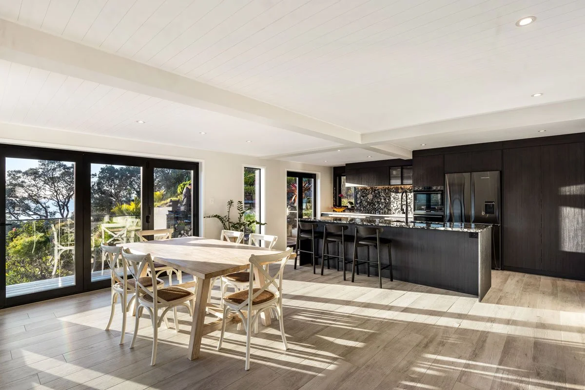 Open-plan kitchen and dining area renovation with full-height joinery and glass doors to deck