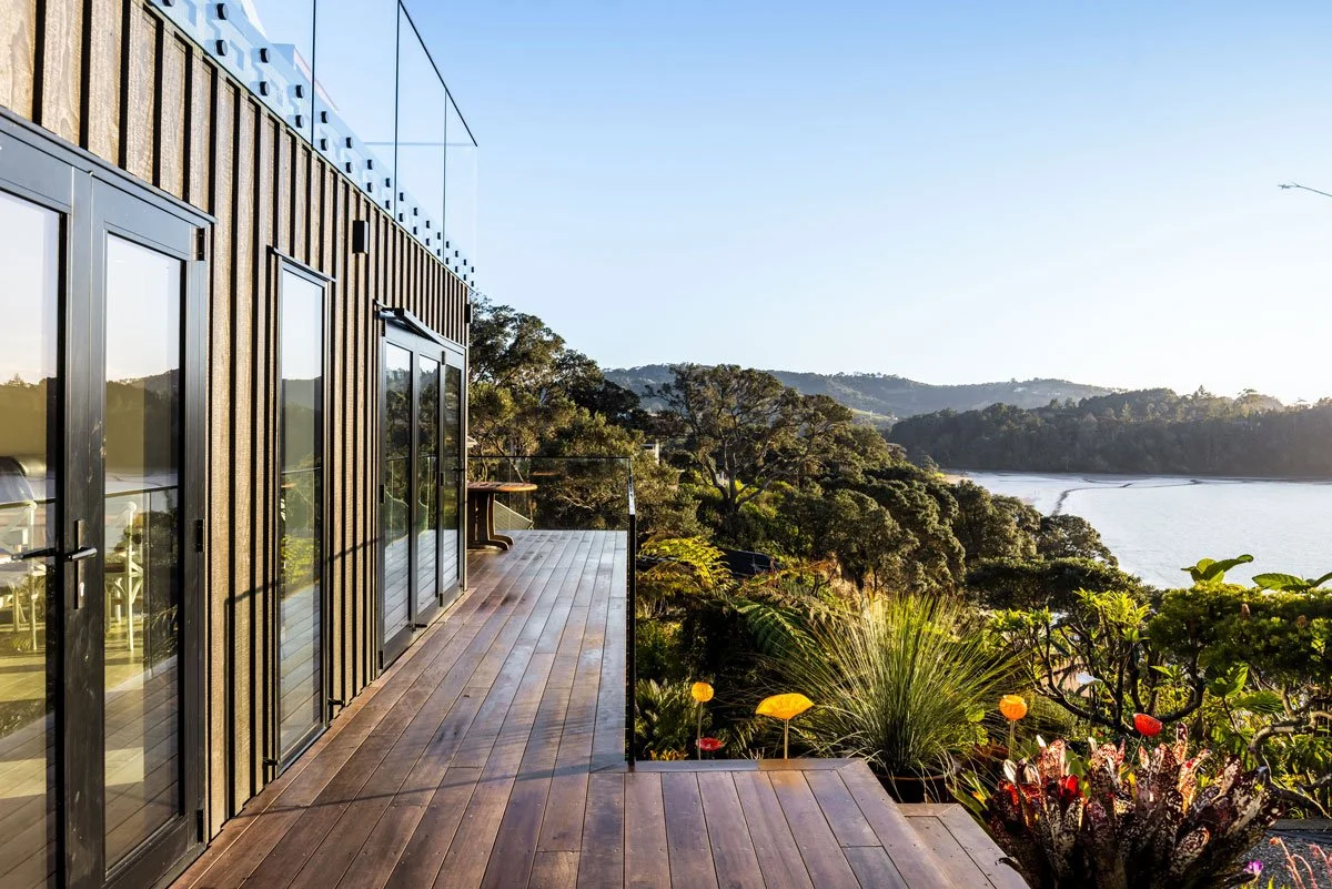Renovated home in Hatfields Beach featuring dark timber board and batten cladding surrounded by tropical planting