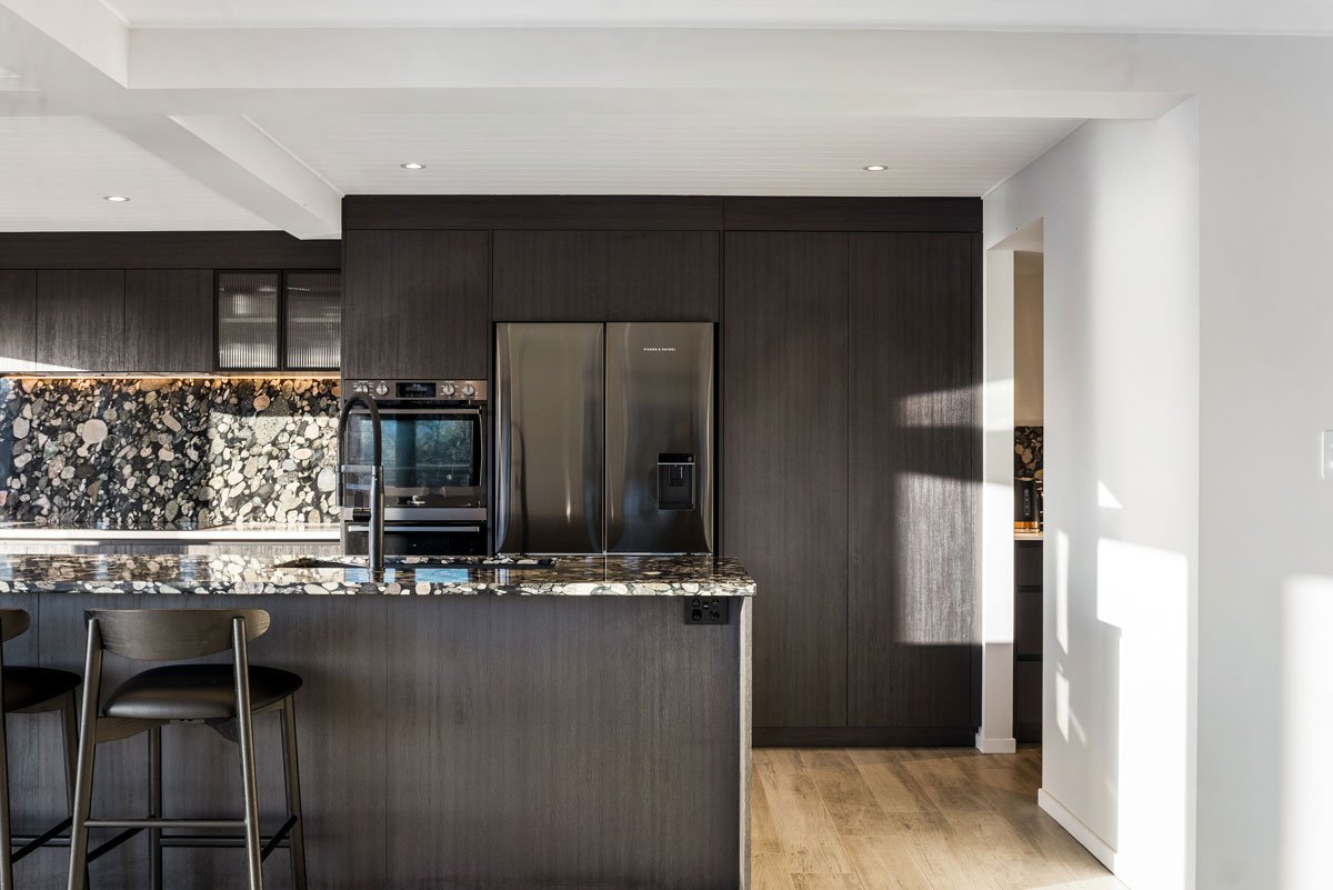 Spacious open-plan kitchen and dining with premium finishes and seamless deck access