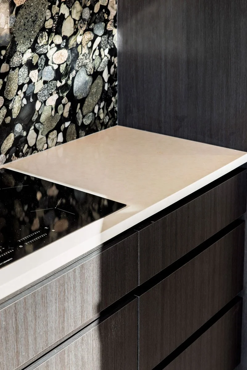 Custom dark kitchen with integrated appliances and terrazzo-style splashback in Auckland renovation