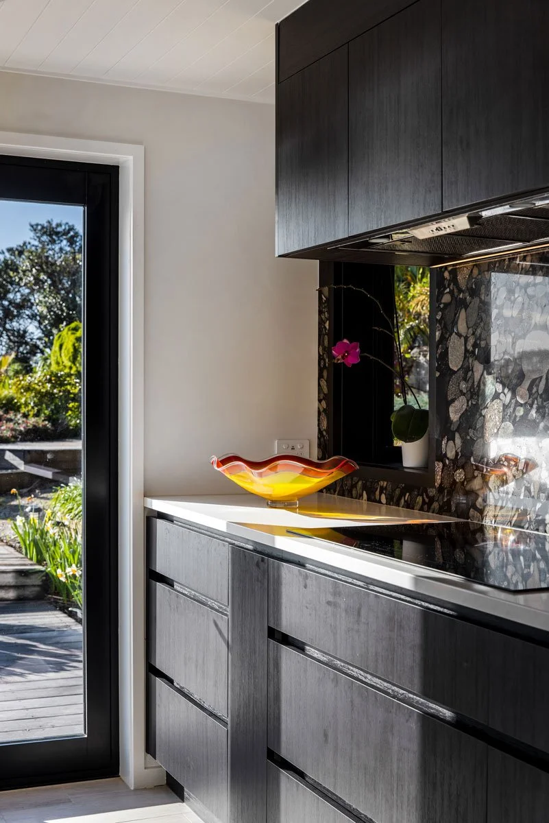 Renovated Auckland kitchen featuring dark cabinetry and statement terrazzo splashback