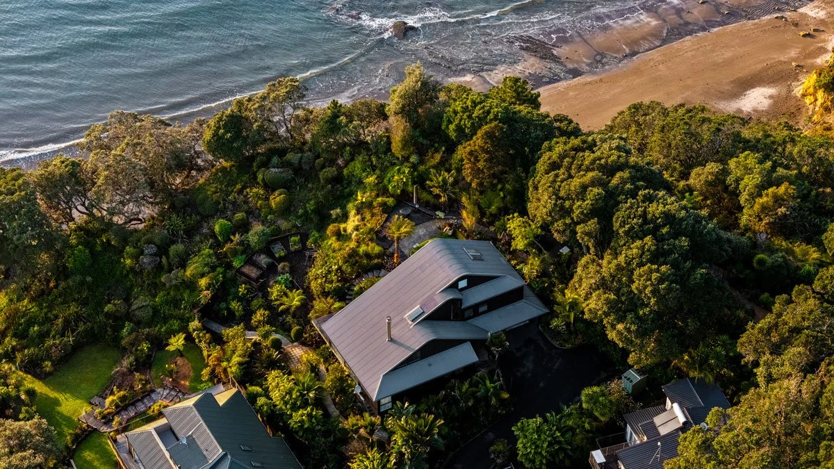 New multi-level Kanda hardwood decks with frameless glass balustrades overlooking Hibiscus Coast bush and sea.