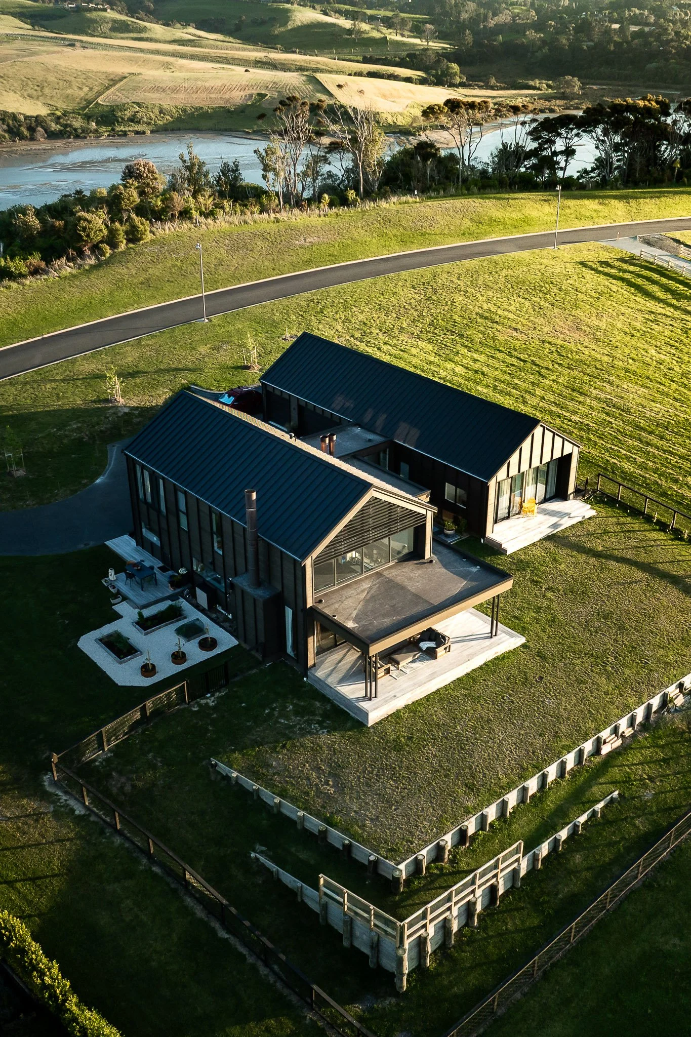 Warm oak flooring, soft natural tones, and large sliding doors opening to sheltered deck—framed by countryside and bay views.