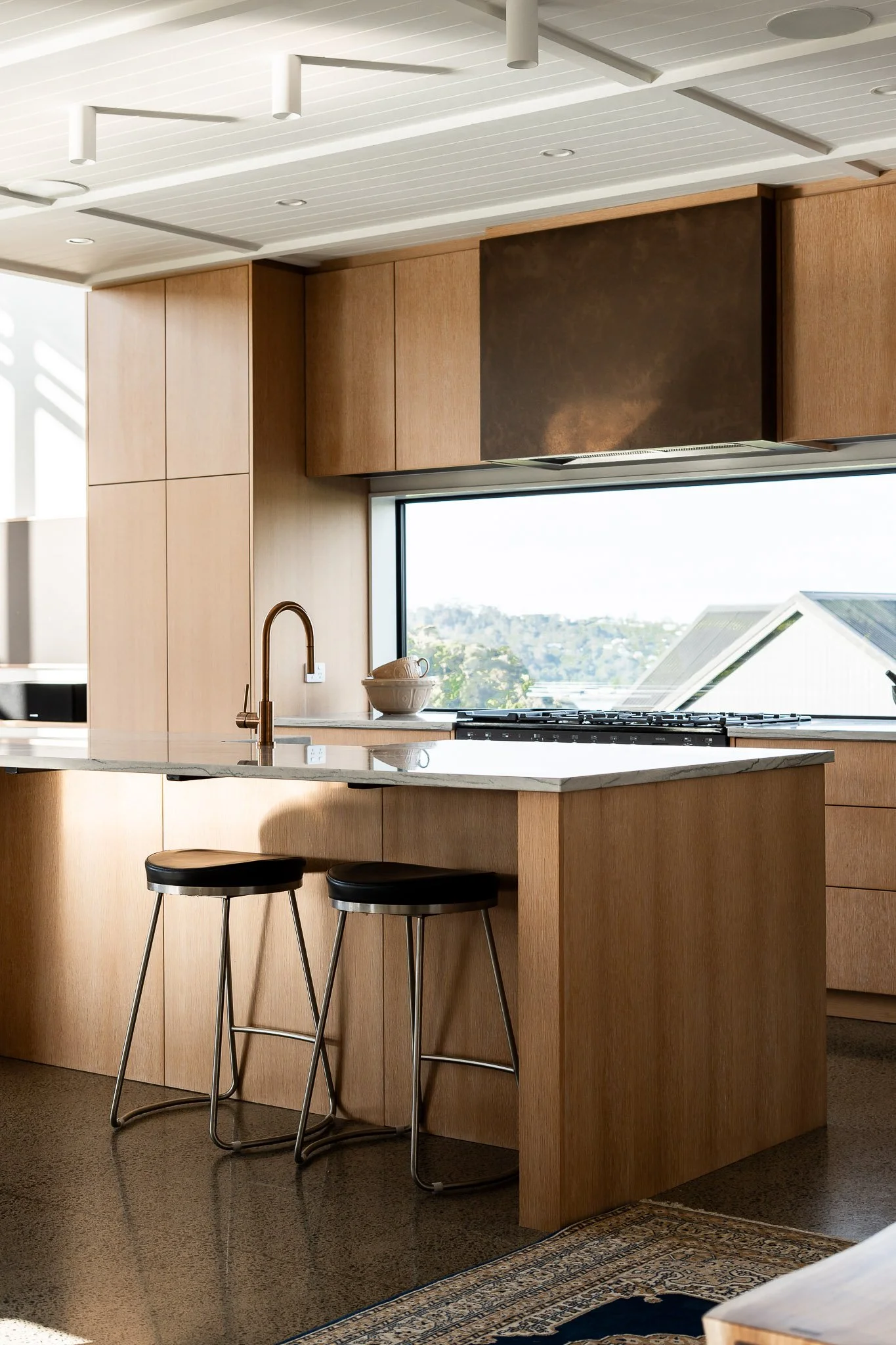 Floor-to-ceiling windows bringing the outdoors in with views to native trees and the coast.