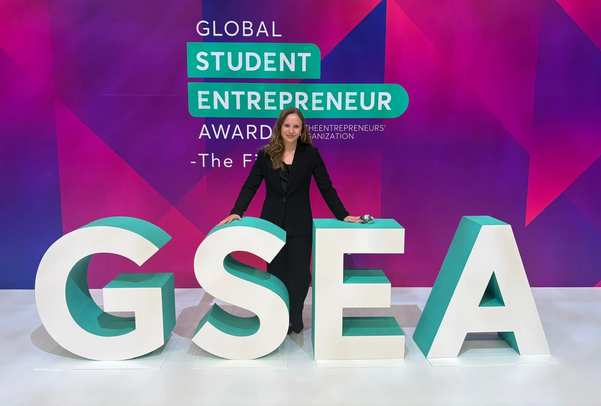 College founder standing on the main stage of the Global Student Entrepreneur Awards (GSEA) competition.