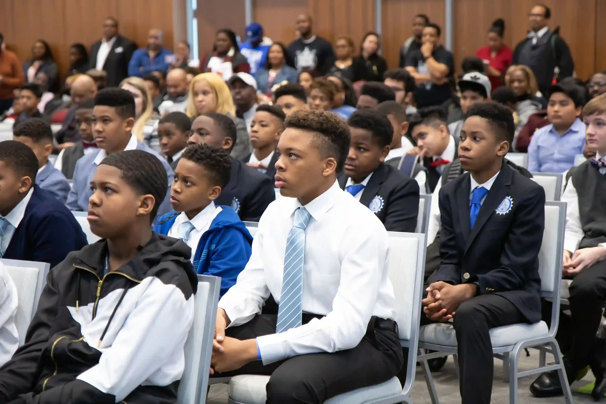 A group of focused young students attending a youth business competition presentation for teenagers.