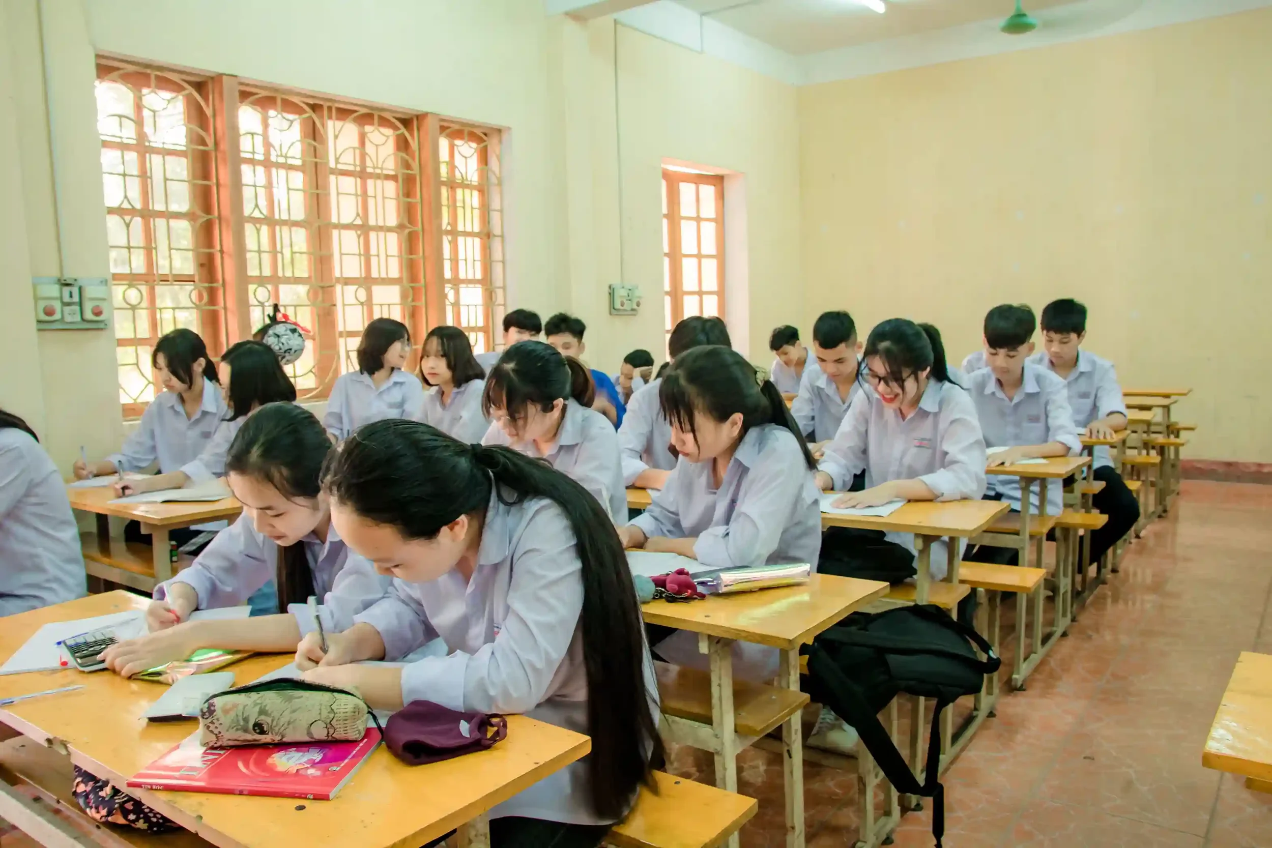 High school students in uniforms sitting at desks in a classroom, representing the need for financial education in schools.