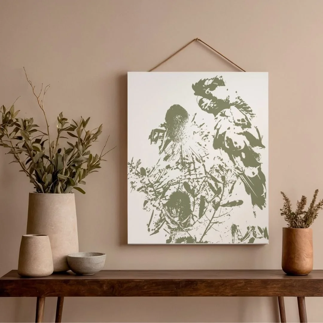 Canvas Wall Art of Black Cockatoo among Coastal Banksia native flowers in monochrome sage green, against a warm neutral bohemian style background with terracotta pots and  dried greenery.