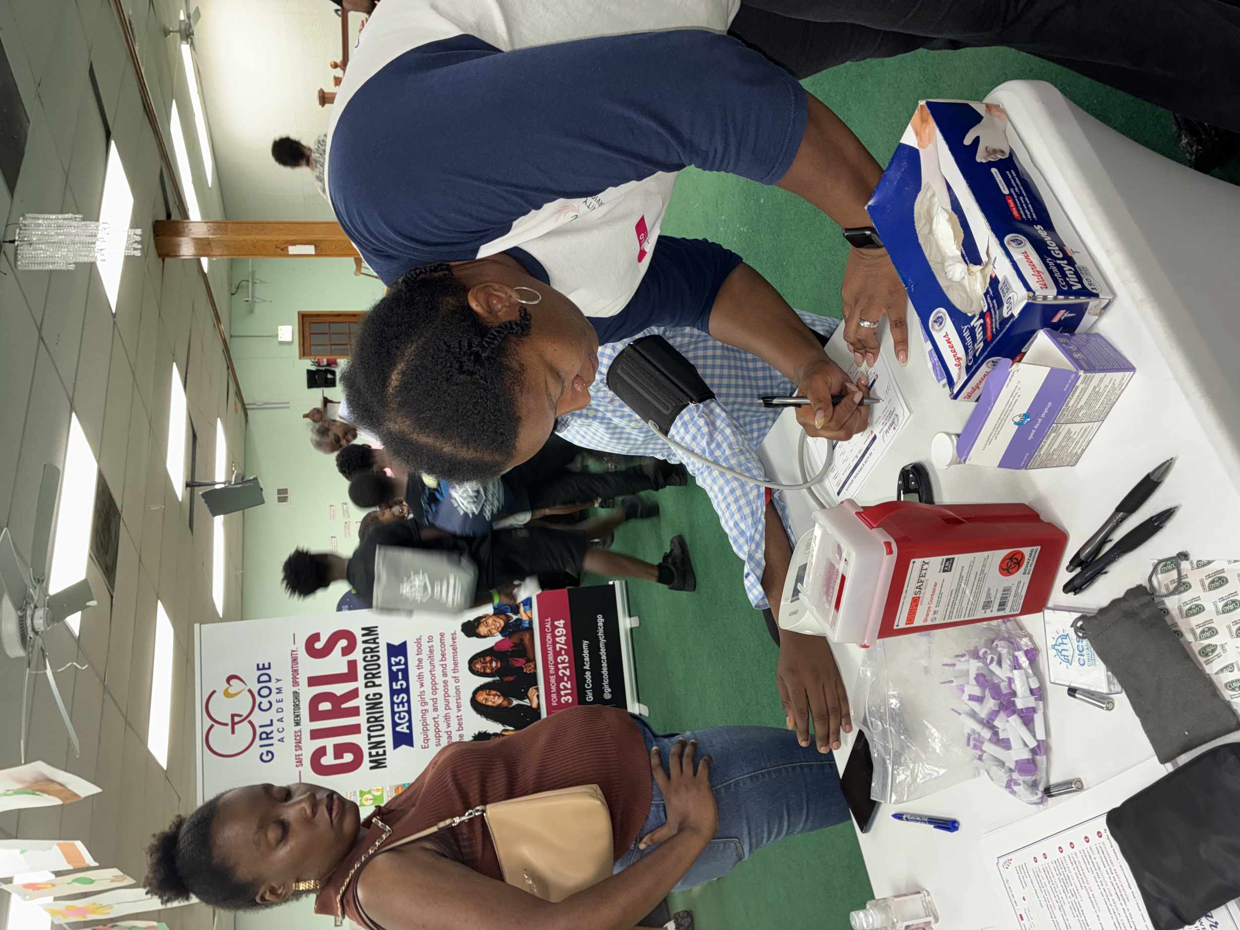 People at an informational booth about girls' education and empowerment, with brochures and promotional materials displayed on the table.