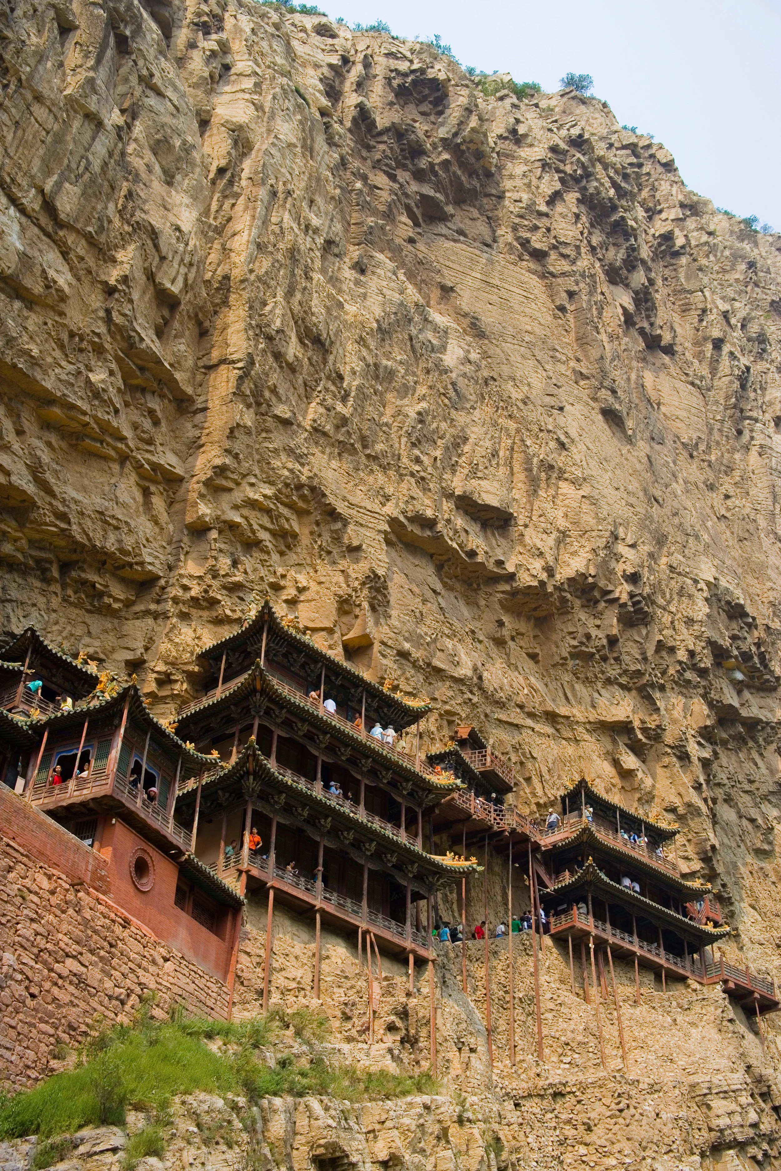 Traditional Chinese temple built into a cliffside with multiple levels and ornate, curved roofs, surrounded by rocky terrain and some greenery.