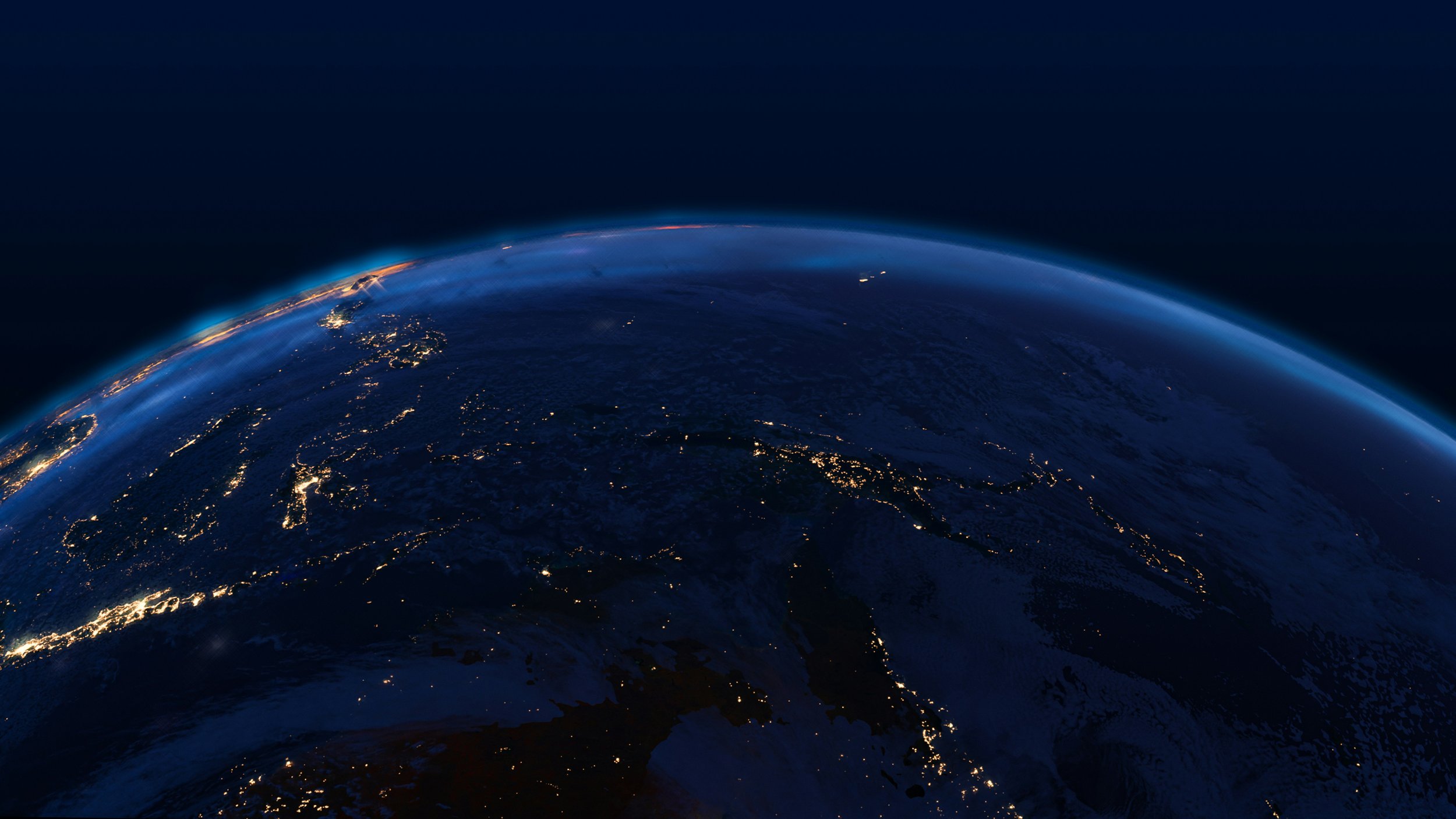 View of Earth from space at night, showing city lights and the curvature of the planet with a dark background.
