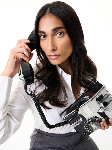 Woman holding a vintage rotary phone and a modern digital phone.