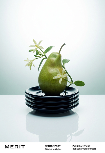 A green pear with flowers and leaves on top, placed on a stack of black plates.