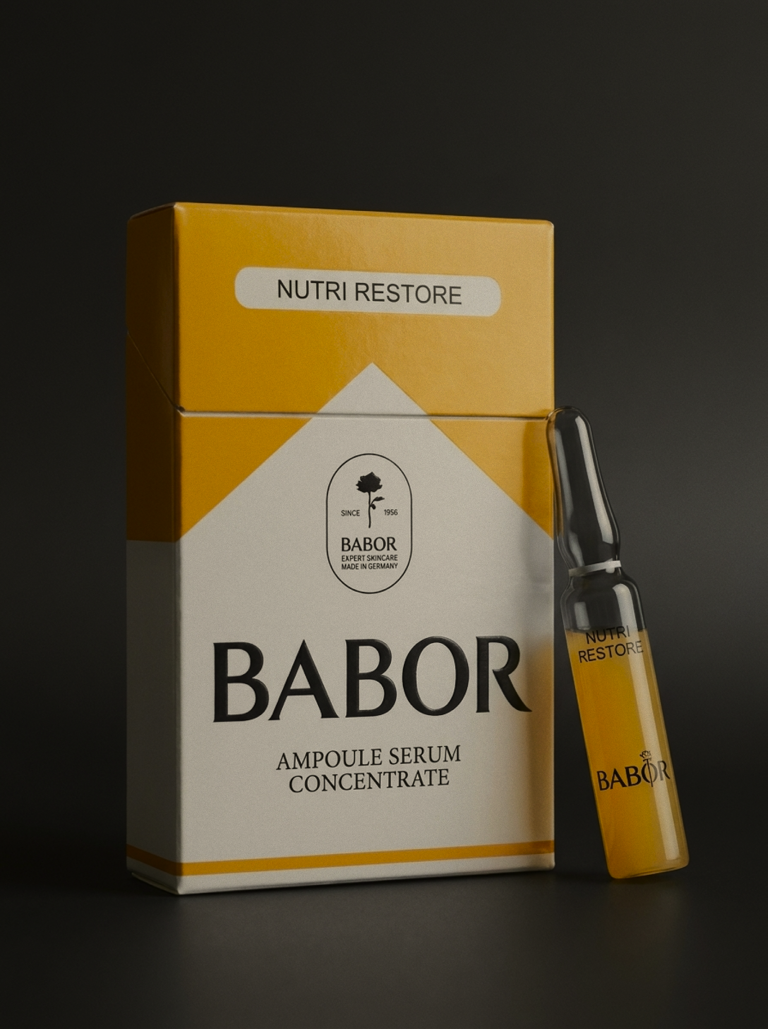 A yellow and white box of Babor Nutri Restore Ampoule Serum Concentrate along with a small vial and a pipette