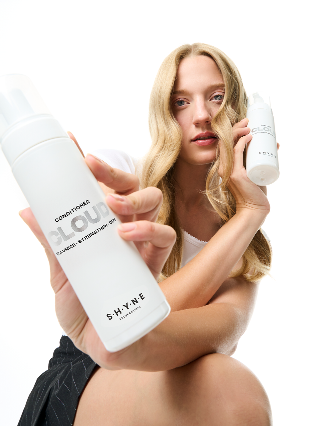 Young woman holding hair care product bottles close to the camera, focusing on the labels.