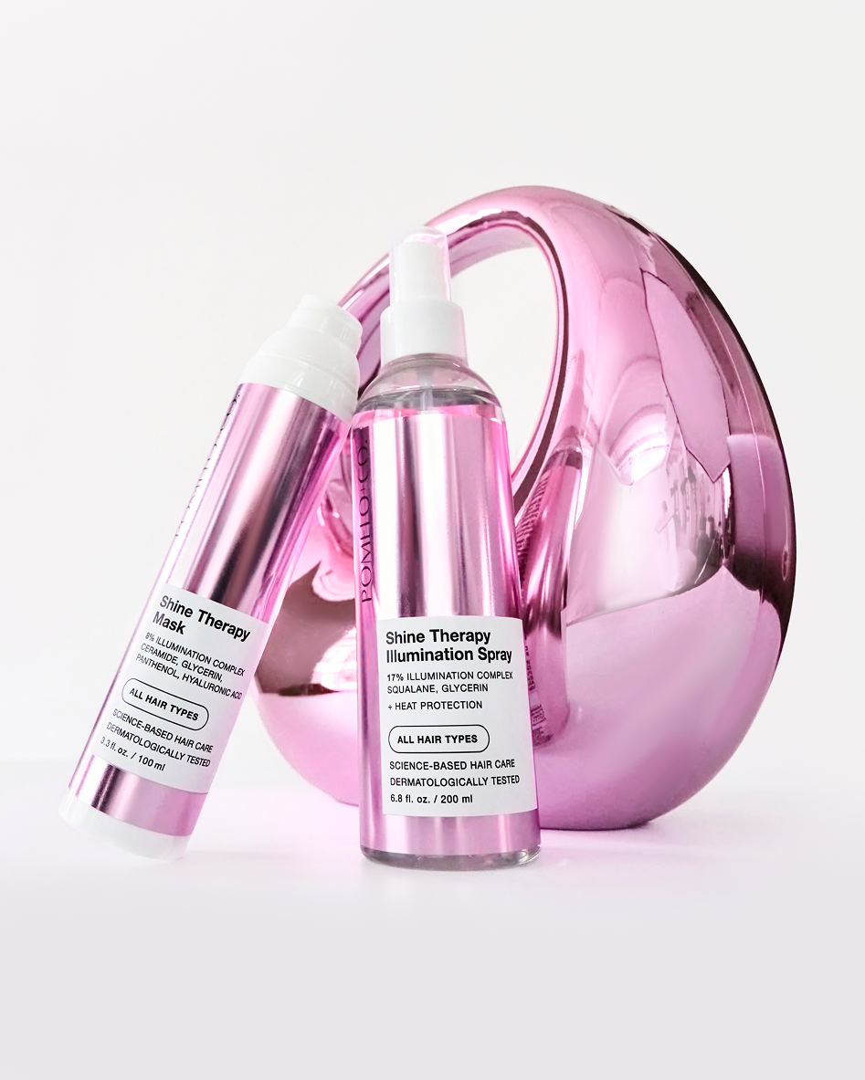 Pink metallic hair care bottles and a pink metallic hairdryer on a white background.