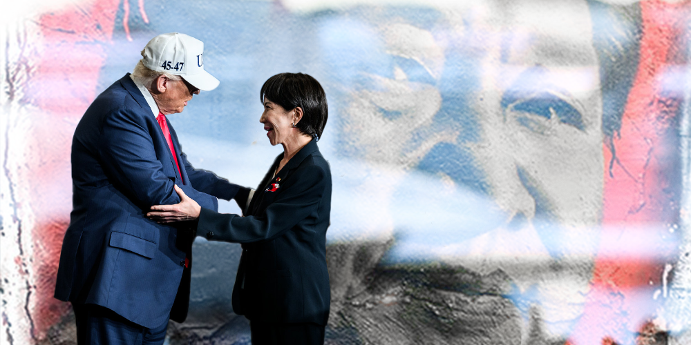 A woman in a black blazer is smiling and shaking hands with a man in a blue suit and red tie, wearing a white helmet, against a background of a large flag.
