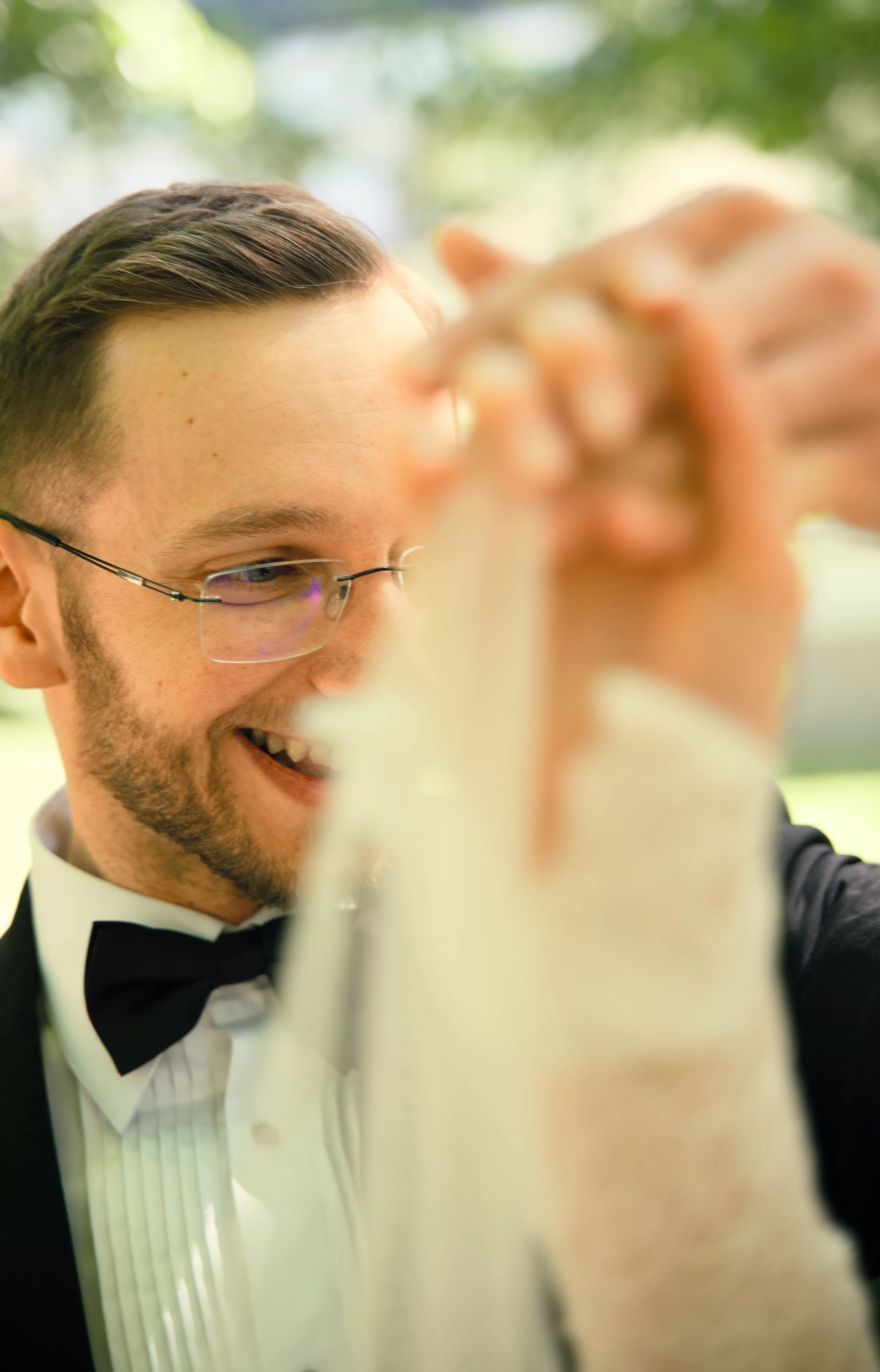 A man in a tuxedo and glasses smiling as he dances at a wedding reception.