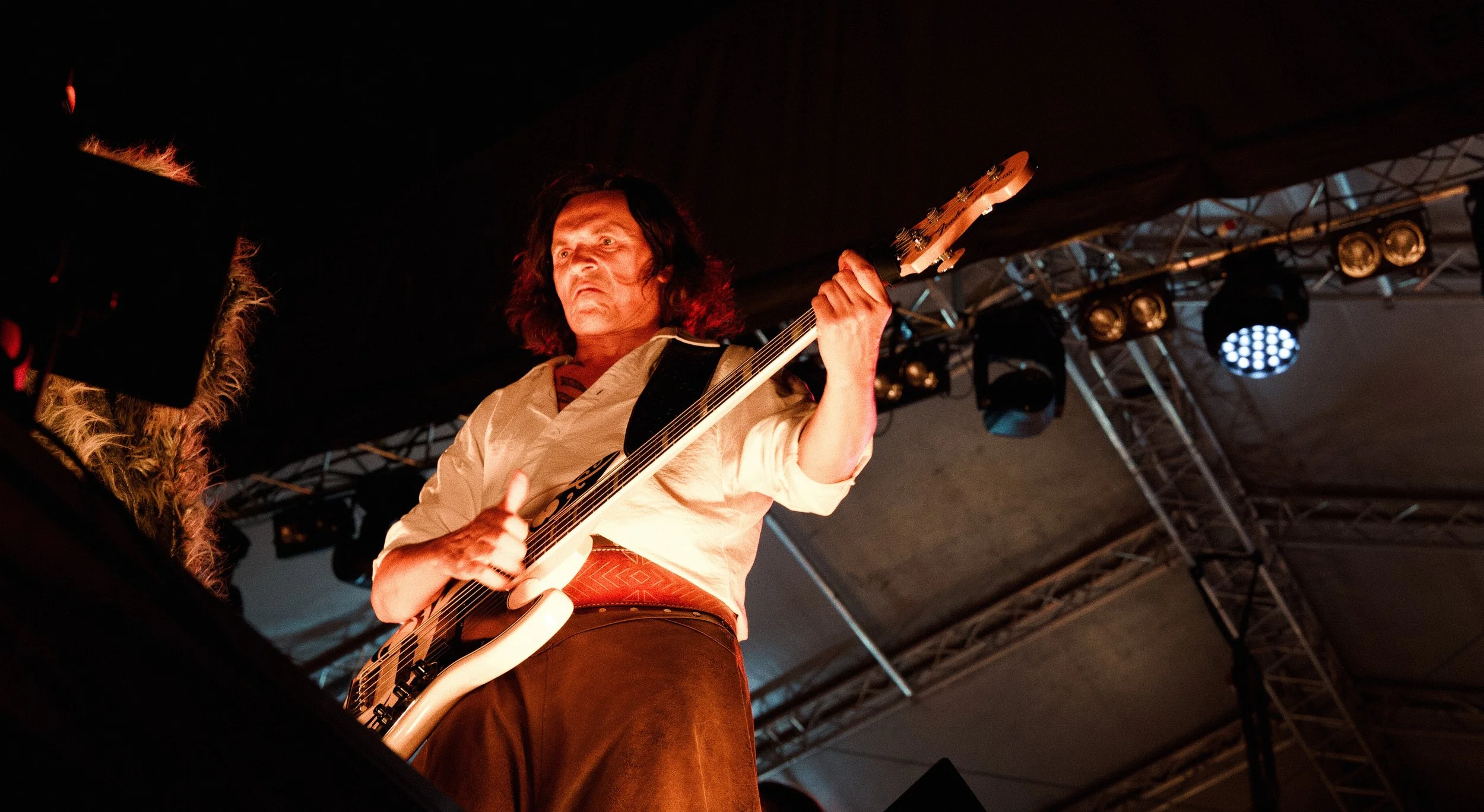 A man playing an electric guitar on stage under stage lights.