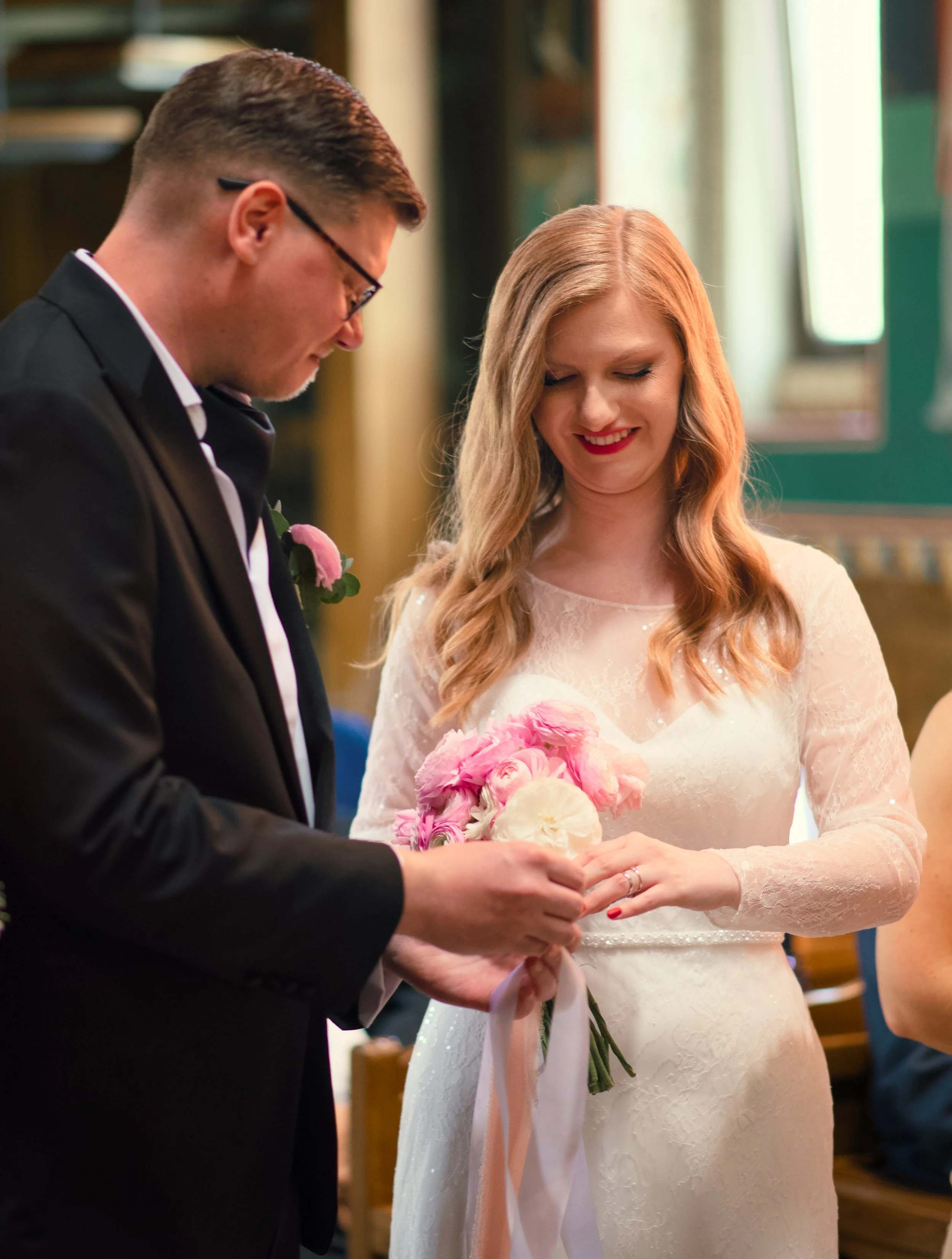 Bride and groom during wedding ceremony, holding a bouquet of pink and white flowers.